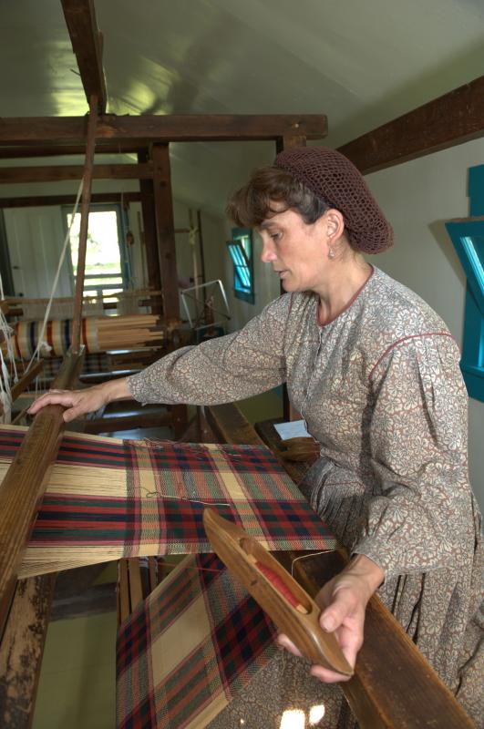 Weaver in historical dress working at a loom