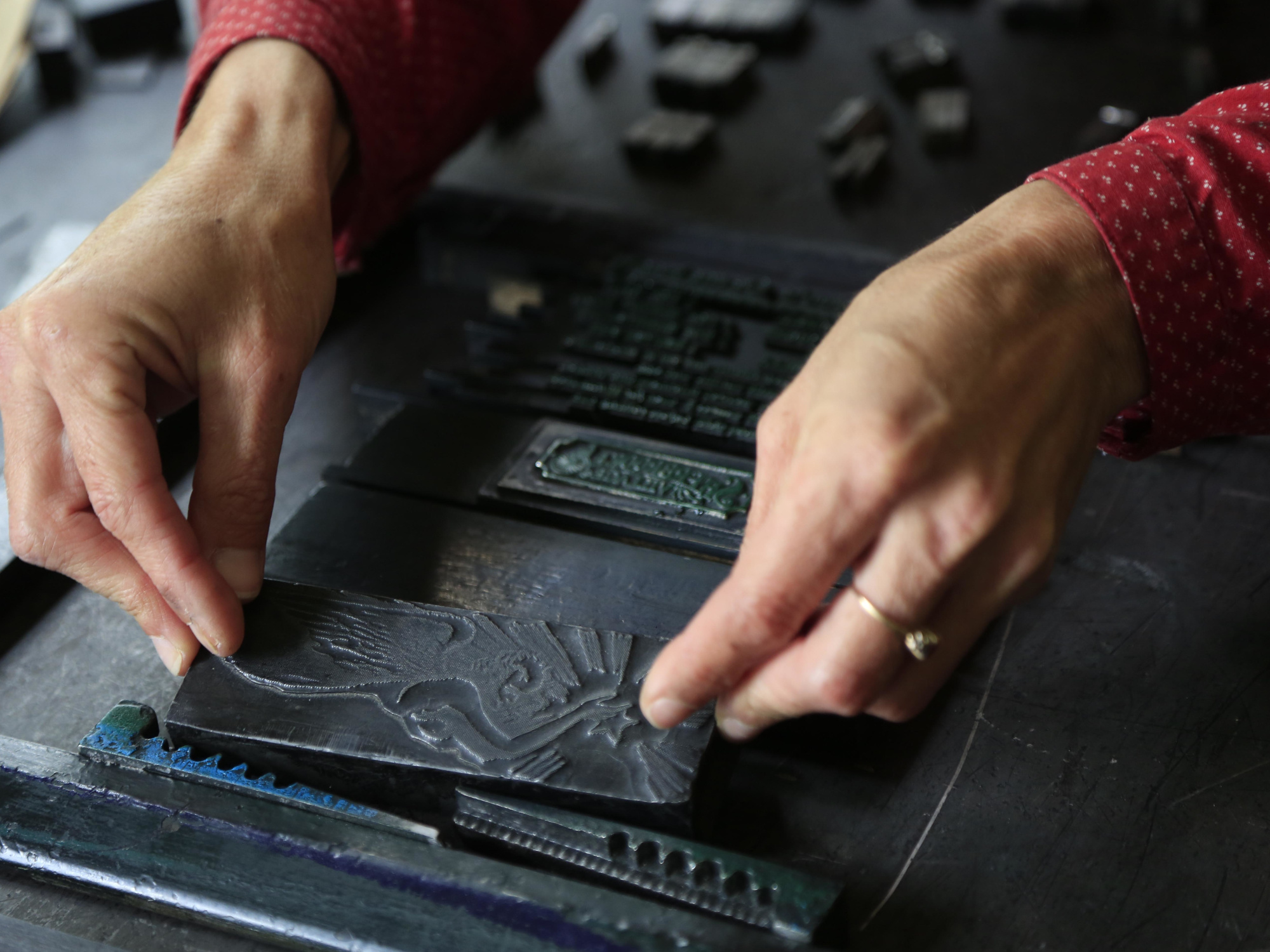 Detail of hands setting up a letterpress printer.