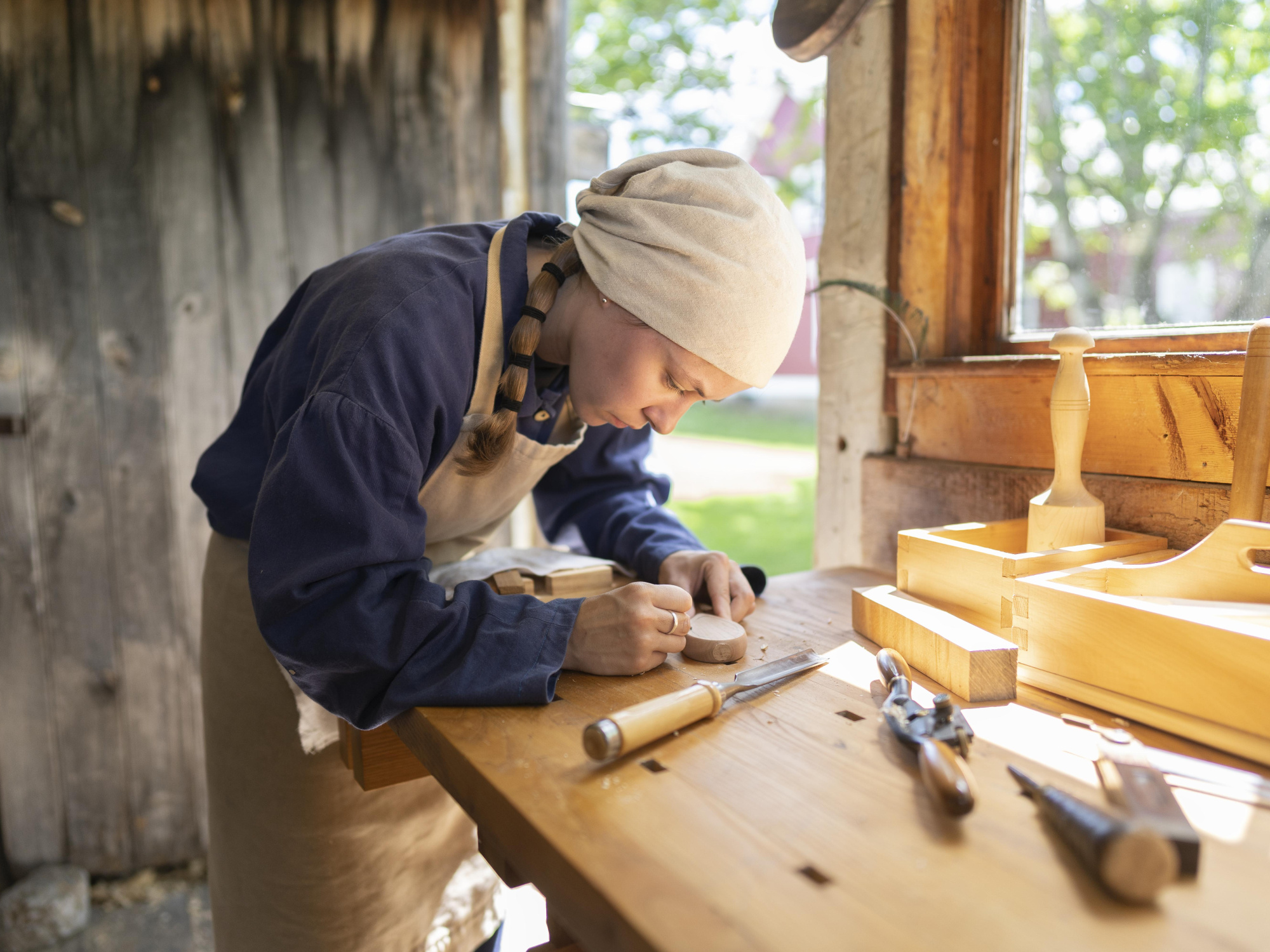 A costumed interpreter working in a wood shop at Sherbrooke Village.