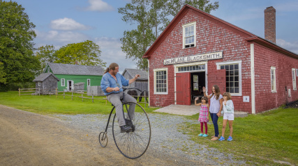 Visitors wave at a costumed interpreter on a penny-farthing 