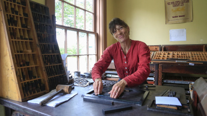 Female costumed interpreter working in the print shop.
